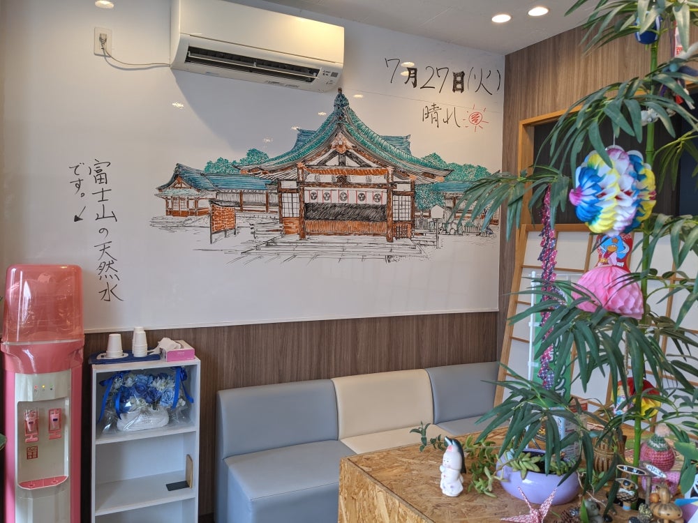 たなばた接骨院の店内の様子の写真 - 受付の真清田神社のペン画と富士の天然水